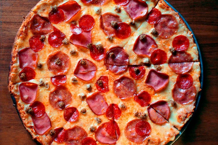A spread of Desi pizzas arranged on a catering table with garnishes and serving utensils