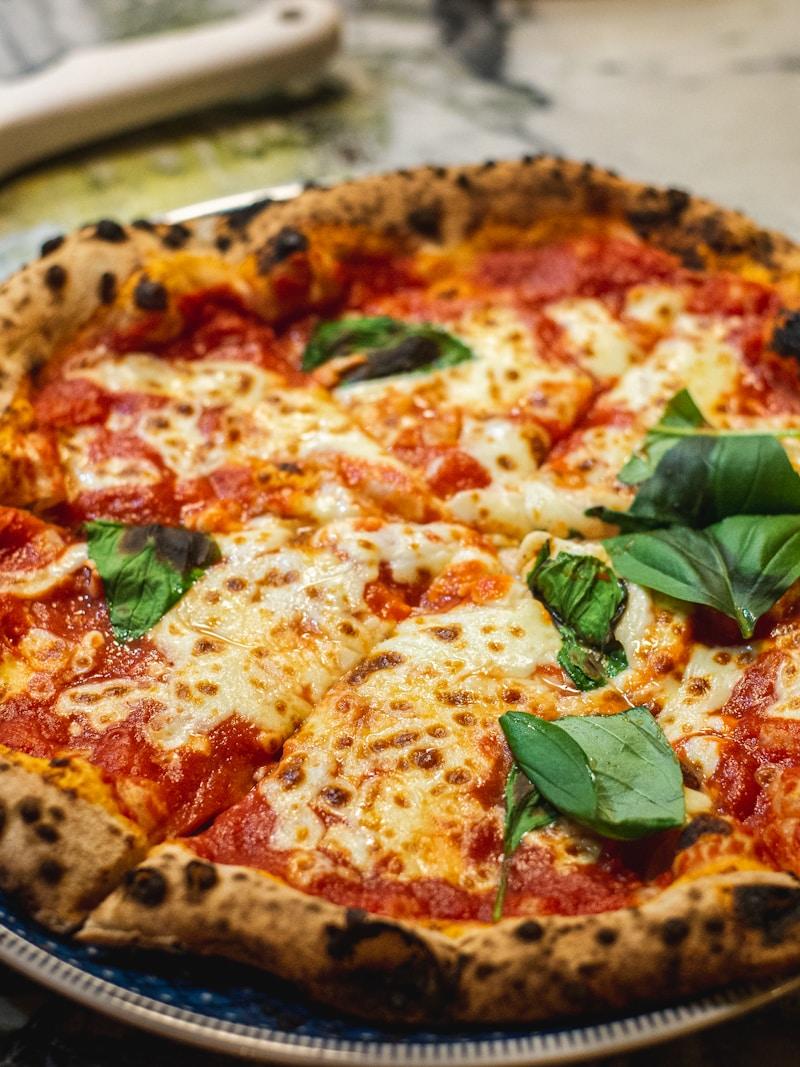 A pizza chef stretching fresh dough by hand in the Desi Pizza House kitchen